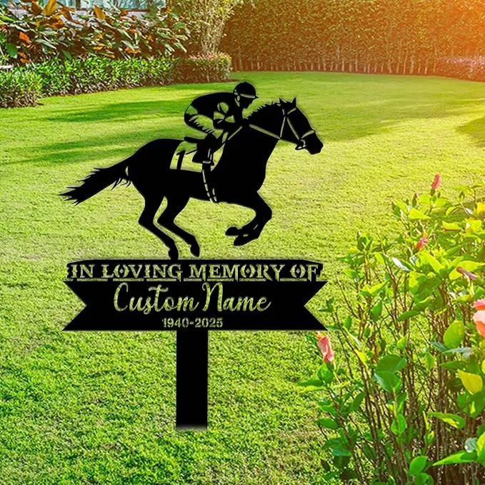 Black metal memorial yard sign showing a jockey on a horse above text 'In Loving Memory of Custom Name 1940-2025' placed on a sunny green lawn near flowering shrubs