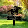 Black metal memorial yard sign showing a jockey on a racehorse above text 'IN LOVING MEMORY OF' and 'Custom Name 1940-2025' staked in a sunlit garden