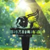 92-1 Black metal memorial stake shaped like a winged lion head with grass, name "SMILEY" and dates "2021 - 2024" against a sunlit forest background with butterflies