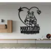 Black metal wall art in a living room showing two crowned frogs inside a heart, text “MARA & DAVID 2022” and “TOGETHER UNTIL WE CROAK,” mounted above a low console