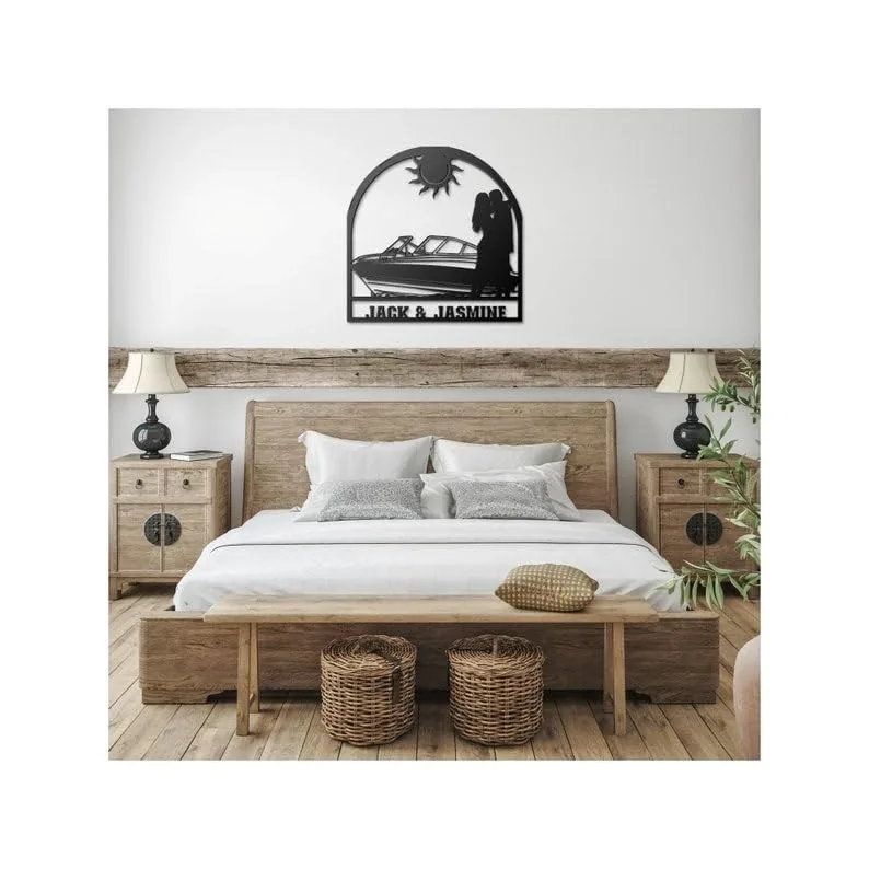 Rustic bedroom with wooden bed and nightstands, personalized black metal wall art above bed showing boat, couple silhouette and the names "Jack & Jasmine"