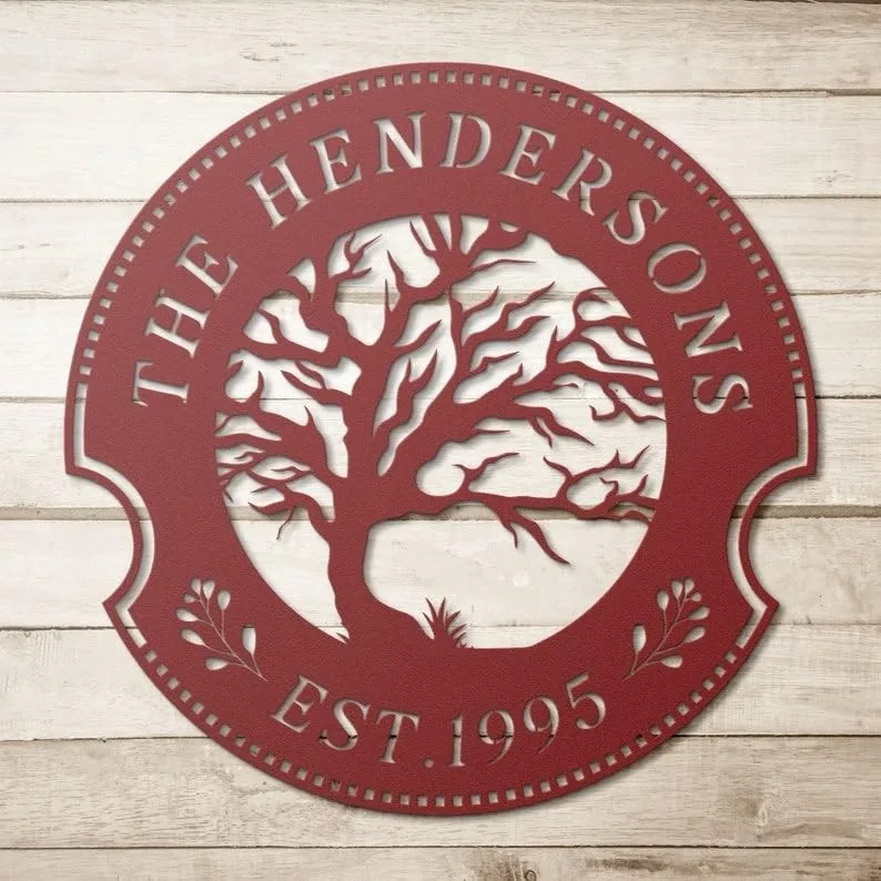 style-19.-Oak-Tree-Couple-1 Red circular metal family name sign reading "The Hendersons" with a tree cutout and "EST. 1995" on a light wood background