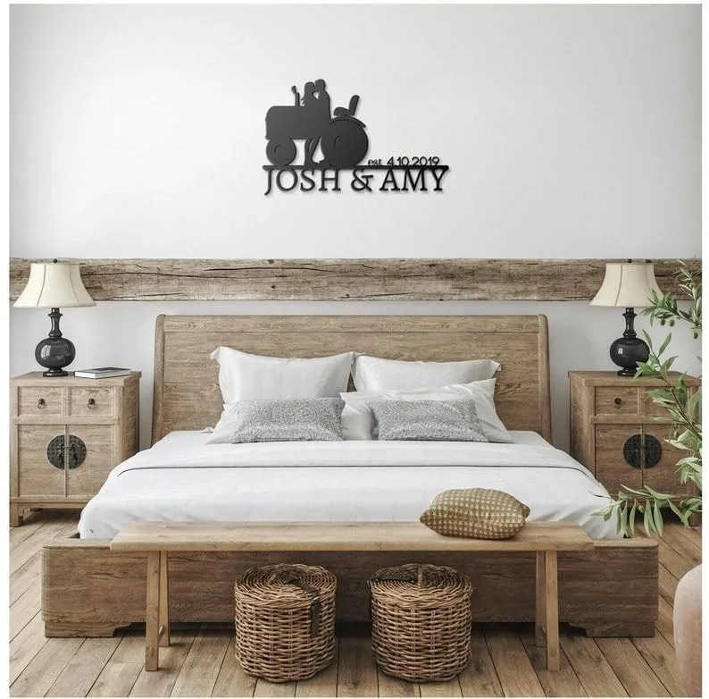 style-20.-Farmer-Tractor-Couple-3 Rustic bedroom with wooden bed, nightstands and lamps, wall sign above bed reading "Josh & Amy" with tractor silhouette and date