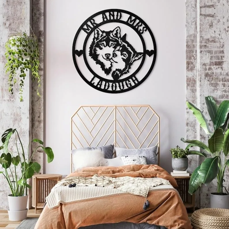 Cozy bedroom with rust-colored bedding, geometric gold headboard, hanging plant and black circular wall art reading "MR AND MRS TADDOUGH" featuring two wolf faces