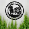 style-23.-Gothic-Skeleton-Couple-1 Black metal circular wall sign reading "Morris & Mary 50th Anniversary" with skull bride and groom silhouettes, mounted on a light wall above green plants
