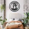 Round black metal wall sign reading "MR & MRS MARKSON EST. 2024" with a kissing couple on bicycles, hanging above a bed in a plant-filled bedroom