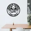 Black circular metal wall sign reading "Jesse & Cheryl 50 Years Together Est. 1974" with two cat silhouettes, displayed above a wooden desk in a minimalist room
