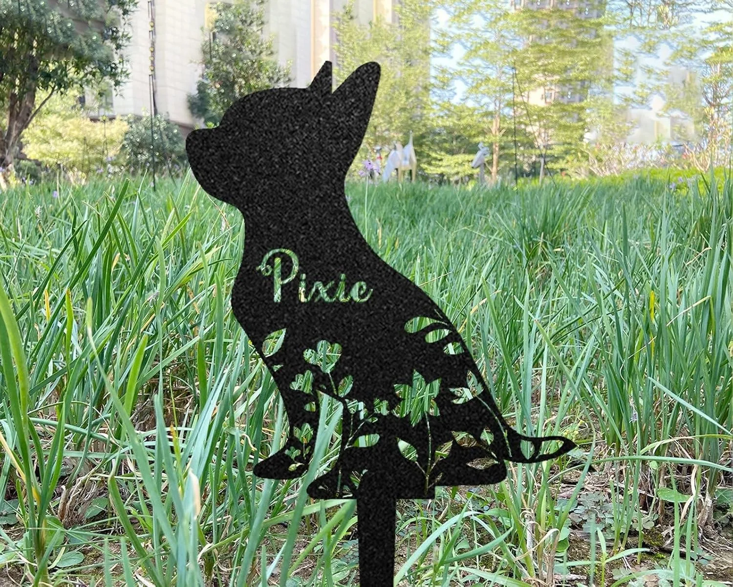 372 Black metal cat garden stake with floral cutouts and the name “Pixie,” placed in grassy outdoor lawn near trees and buildings