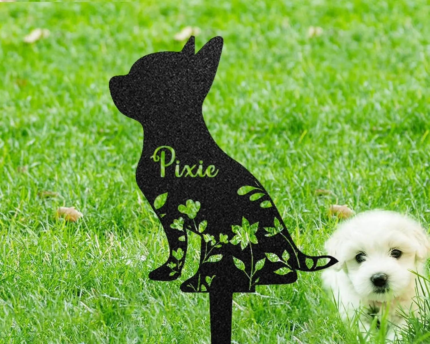 373 Black metal dog silhouette yard stake with floral cutouts and the name "Pixie" staked in green grass next to a small white puppy