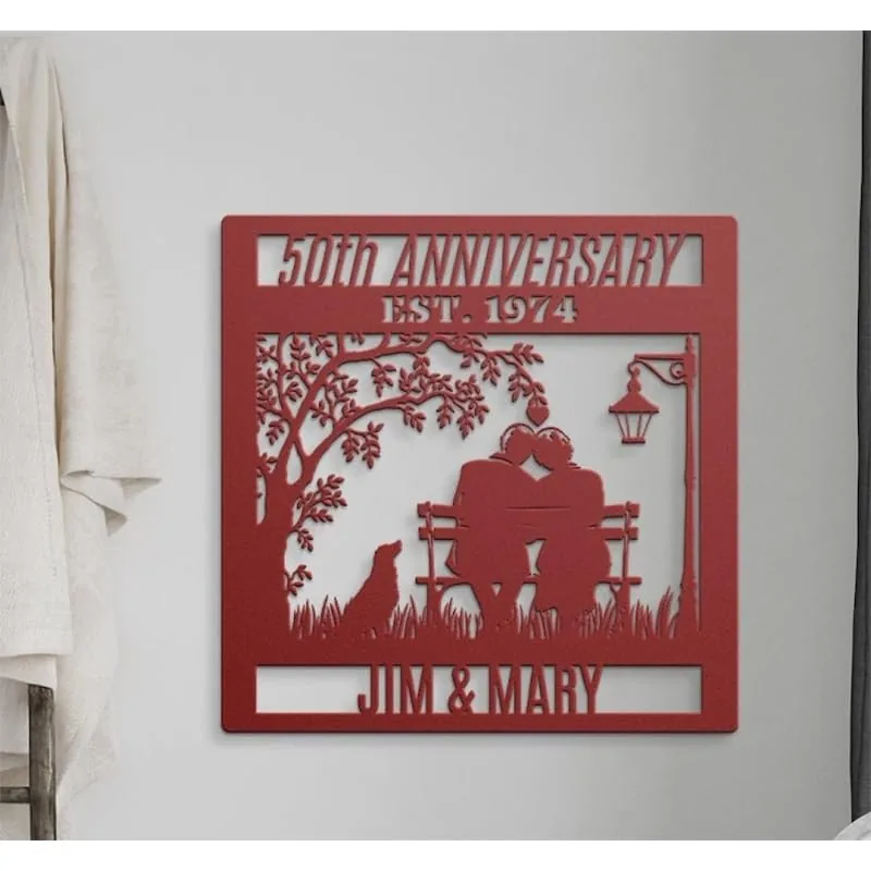 Red metal wall plaque reading "50th Anniversary Est. 1974" with silhouetted couple on a bench, dog, tree, lamp, and names "Jim & Mary" hung on a light wall