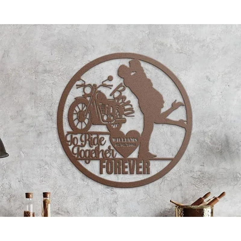 Round metal wall art with a motorcycle silhouette, kissing couple silhouette, and text 'To Ride Together FOREVER' mounted on a textured gray wall